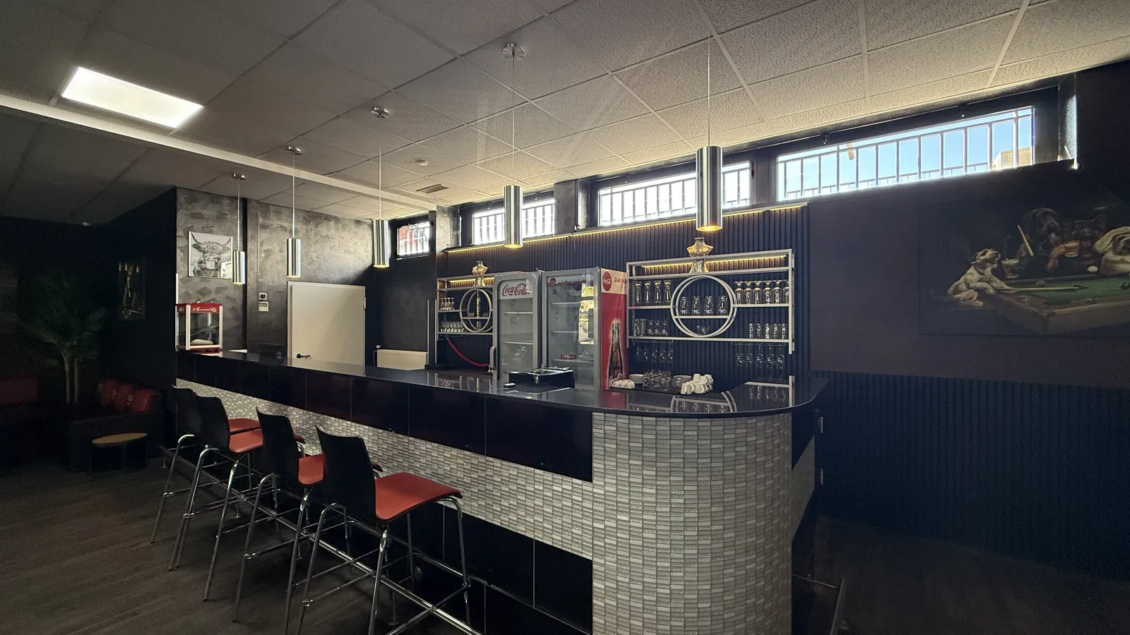Bartheke von Billard Voerde mit heller Mosaikfront, roten Hockern und Flaschenregal