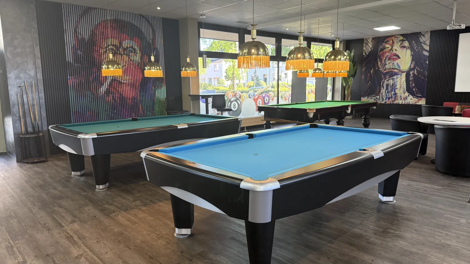 Zwei Pooltische mit blauem Tuch unter goldenen Fransenlampen bei Billard Voerde